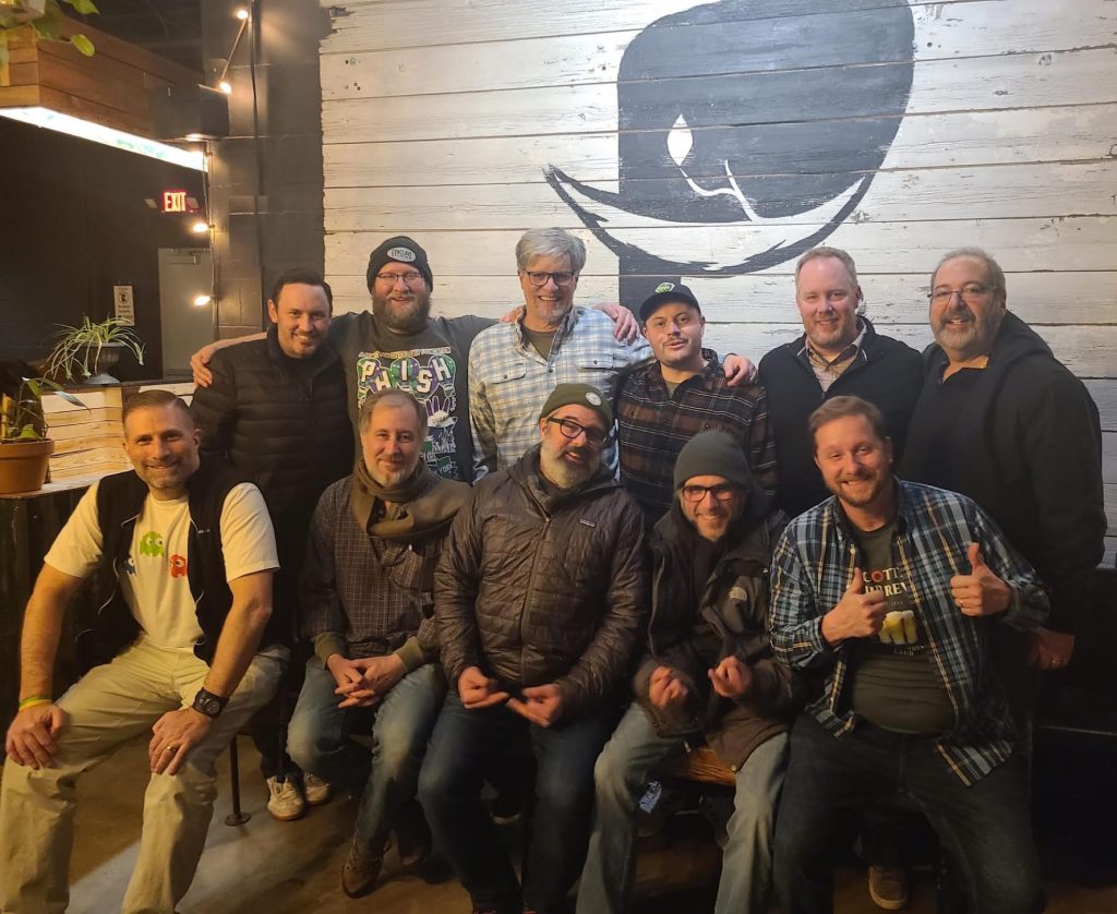 Phish friends Gotta JiBrew Traveling Brewery Club, Top row, Tedd Kanakaris on left & Phish Lyricist Tom Marshall, 3rd person, & Musician Peter Cottone, bottom, 2nd person, played in jam bands with Tom in 1990s & is mentioned in Phish song ‘Wilson’.